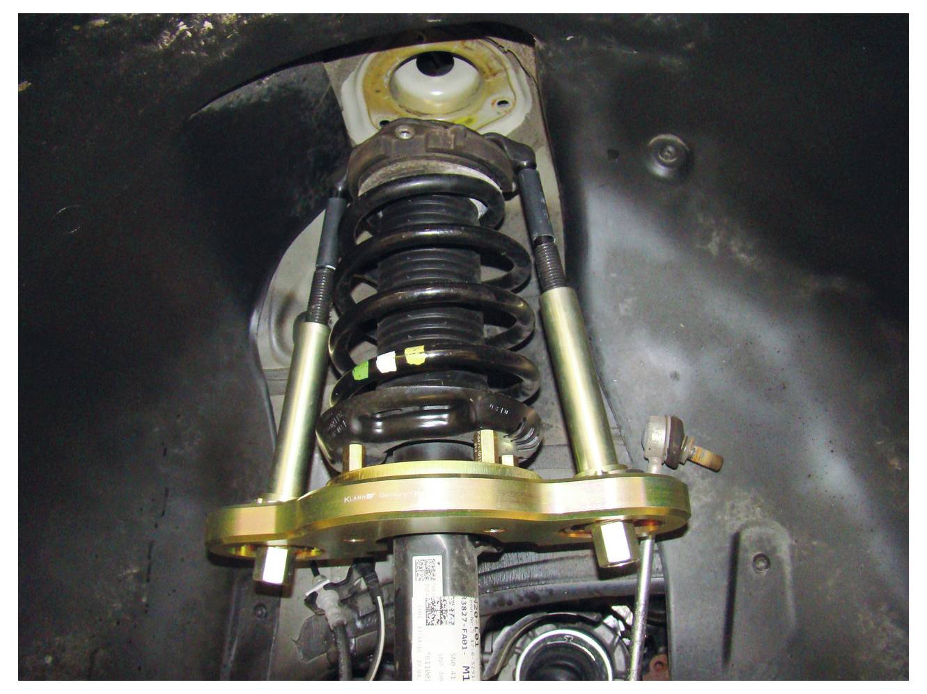 Eine installierte Stoßdämpfer-Fahrwerksanlage zeigt die Schraubenfeder, den Stoßdämpfer und die Befestigungsbrackets im Radkasten.