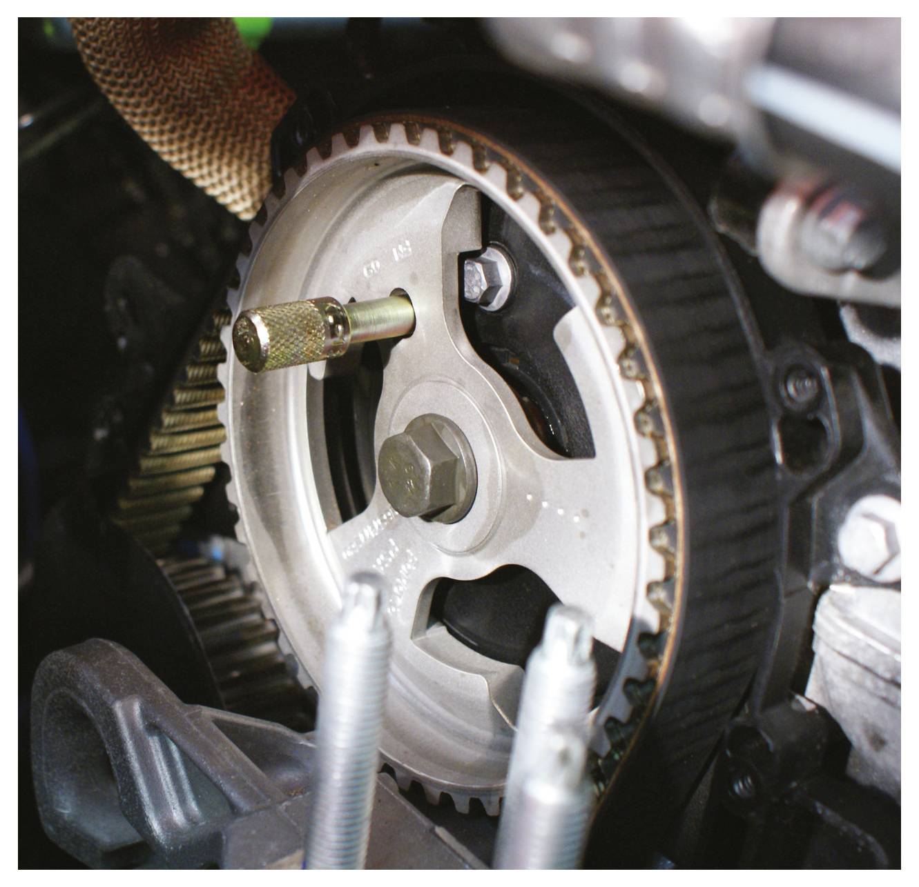 Ein Zahnriemenrad für die Motorzeitsteuerung mit sichtbarem Verriegelungswerkzeug, das bei mechanischen Wartungs- oder Reparaturaufgaben verwendet wird.