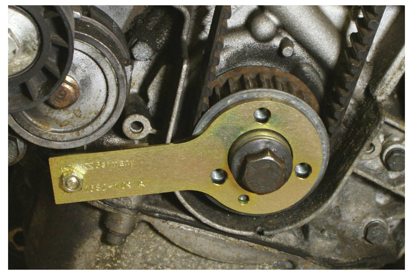 Ein Schraubenschlüssel ist sicher an einer Schraube an einem Motor befestigt, umgeben von Zahnrädern und mechanischen Komponenten, was die Automobilwartung veranschaulicht.