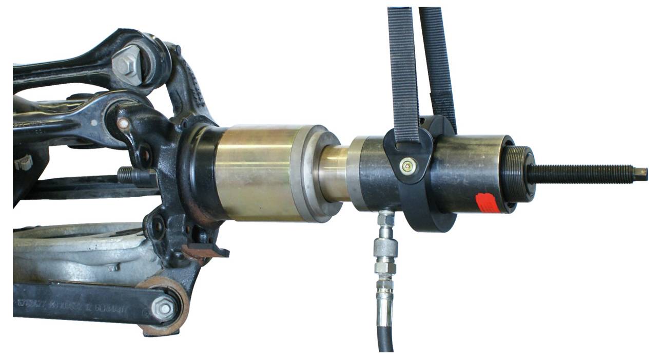 Ein hydraulisches Metallwerkzeug ist an einer Fahrzugaufhängungskomponente befestigt, wahrscheinlich zum Ausrichten oder Reparieren.
