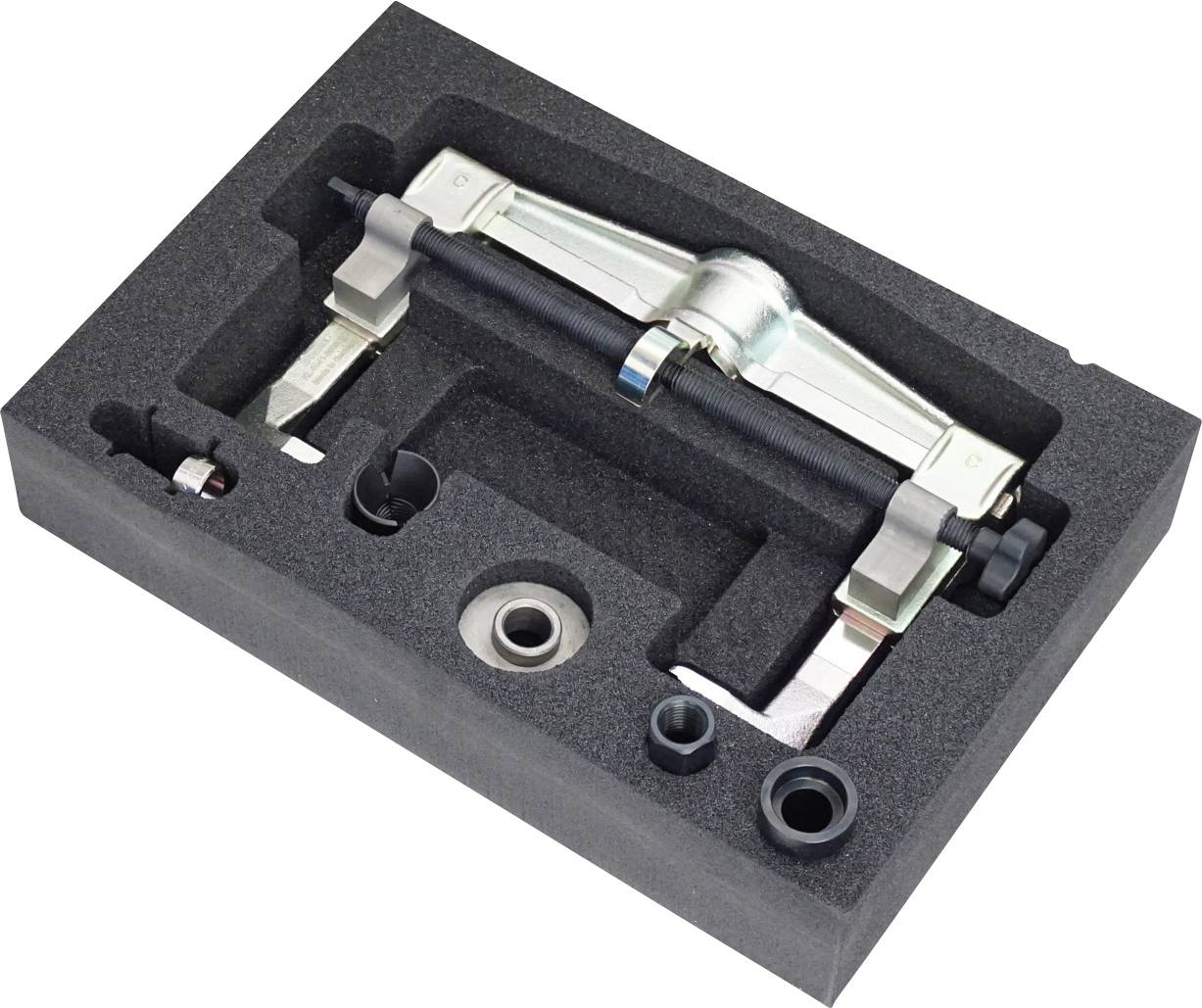 Ein Werkzeugsatz in Schaumstoffverpackung, der einen Abzieher mit metallischen Komponenten und mehrere andere mechanische Teile enthält, die für einfache Zugänglichkeit organisiert sind.