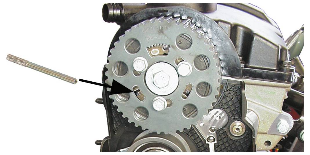 Nahaufnahme eines Motorkomponente mit einem Bolzen, der durch einen Pfeil hervorgehoben ist, und der einen spezifischen Montage-punkt am Kettenrad anzeigt.