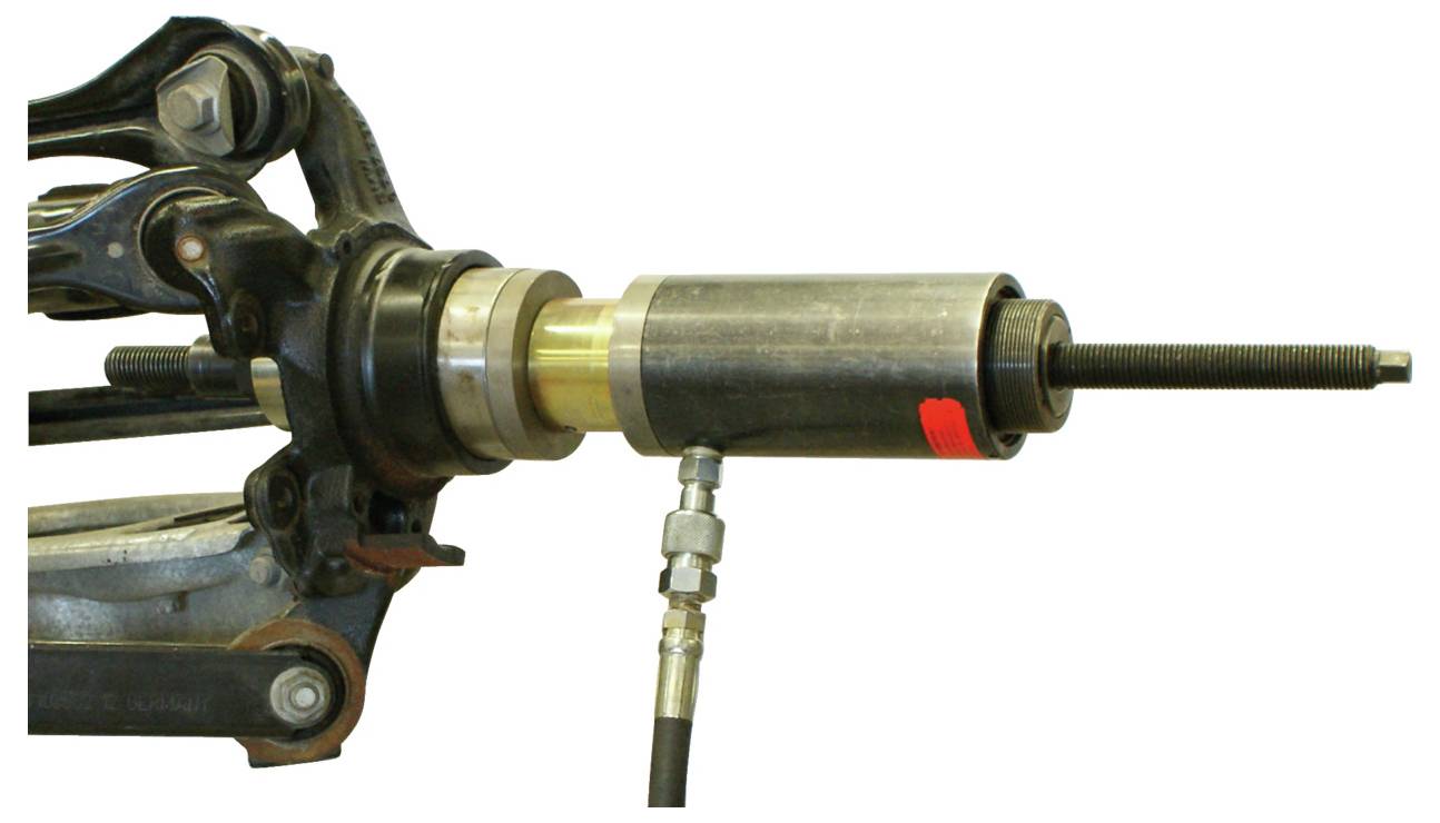 Aufhängungskopplung für Autos mit angebrachtem Hydraulikwerkzeug, wobei mechanische Komponenten und Metallverbindungen für Reparatur oder Wartung gezeigt werden.