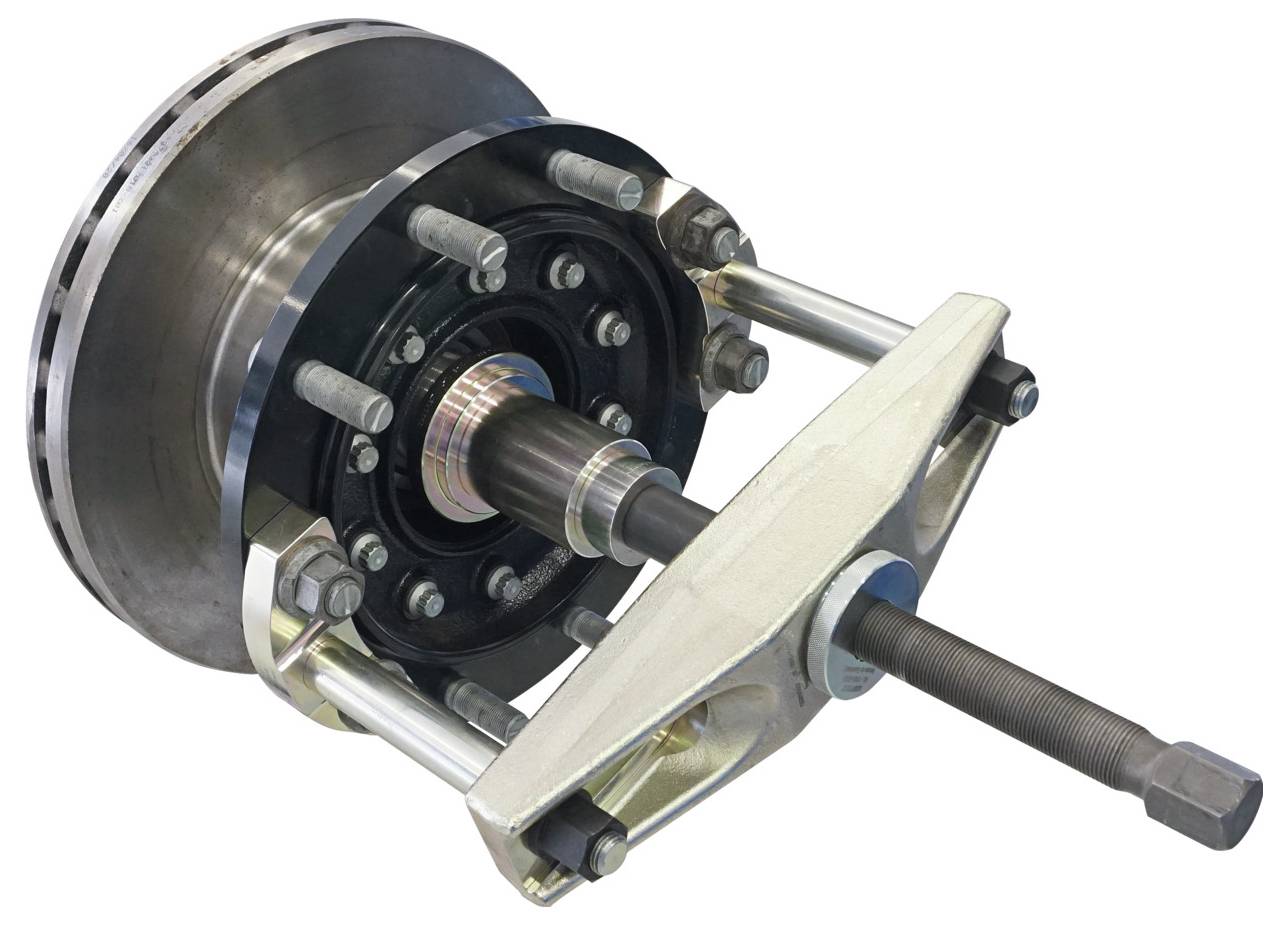 Eine Nahaufnahme eines Bremsscheibenabziehers, der an einer Fahrzeugbremsscheibeneinheit angebracht ist und die Bolzen und den zentralen Spindelmechanismus zeigt.