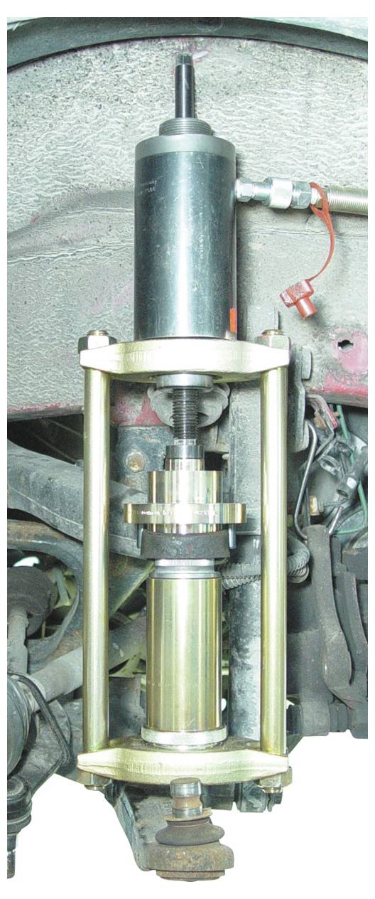 Ein Aufhängungssystem für Fahrzeuge mit einem hydraulischen Gerät, das zu Test- oder Reparaturzwecken installiert ist und verschiedene mechanische Komponenten zeigt.