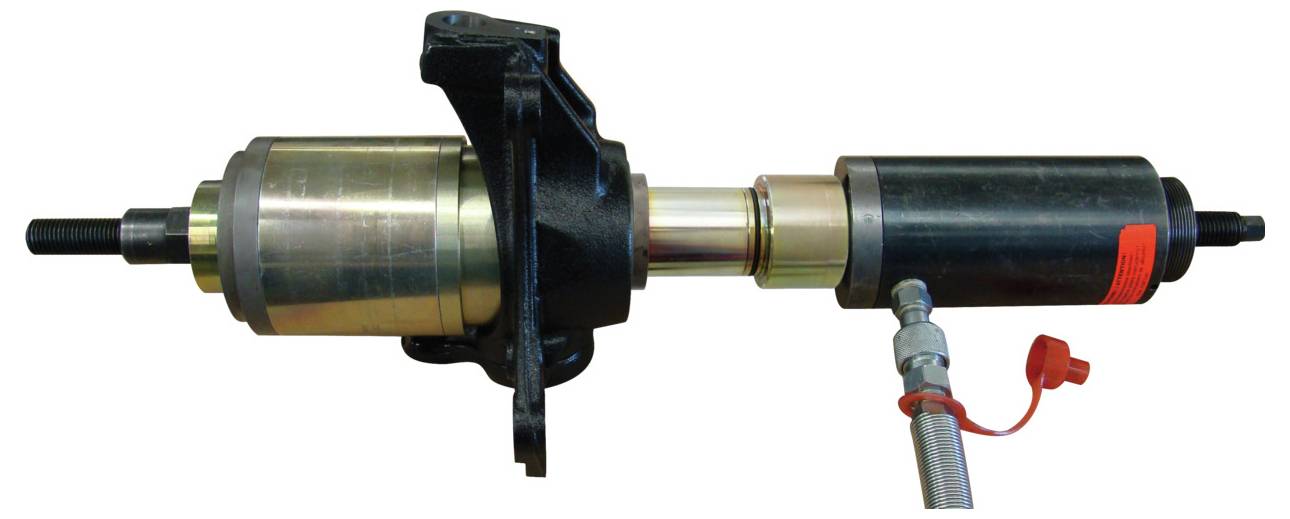 Eine Lenksäule eines Autos mit einem hydraulischen Lenkhilfemechanismus, der Komponenten wie den Aktuator, den hydraulischen Zylinder und die Anschlüsse zeigt.