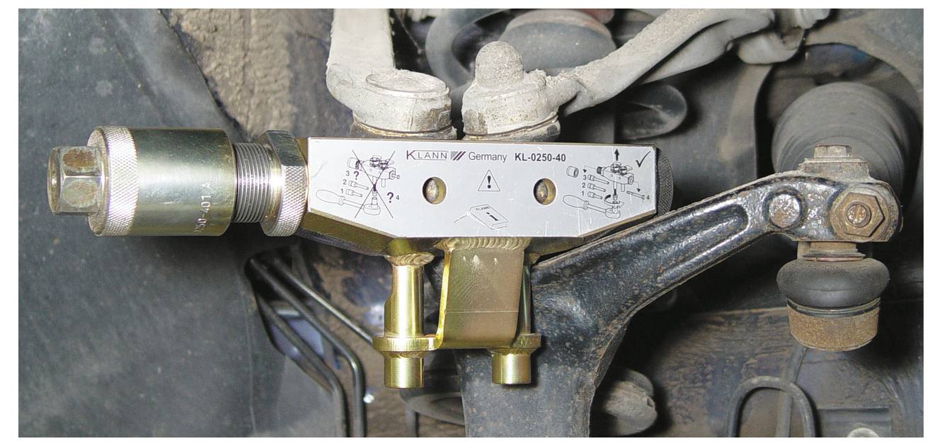 Ein Mechaniker nutzt ein Elektrowerkzeug, um das Federungssystem eines Autos einzustellen.