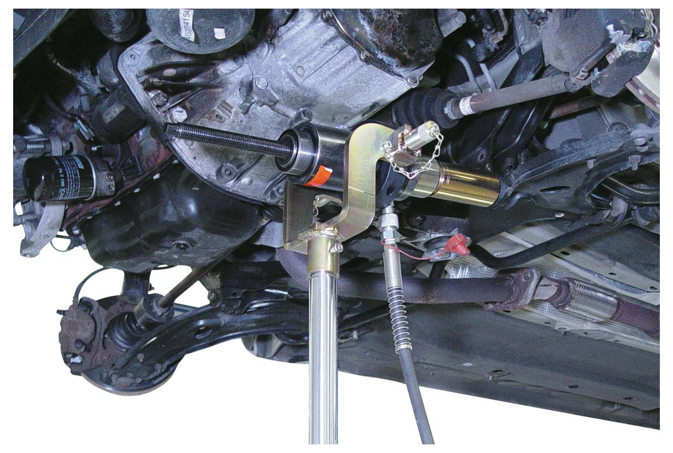 Ein hydraulisches Werkzeug entfernt ein Kugelgelenk aus der Aufhängung des Fahrzeuguntergestells und zeigt mechanische Teile und Verbindungen.