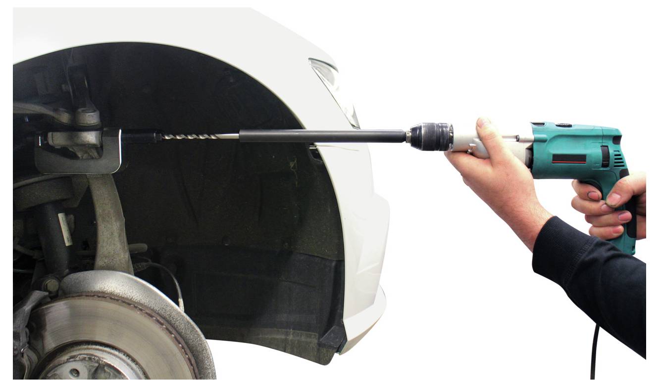 Eine Person benutzt einen Elektroschrauber mit einem langen Bohrer, um an der Aufhängung eines Autos zu arbeiten, dessen Rad entfernt wurde.