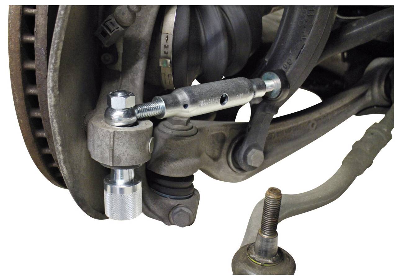 Ein Spurstangenkopf-Abzieher wird an der Lenkachse eines Autos zur Wartung oder Reparatur angewendet und zeigt die mechanische Verbindung und die Komponenten.