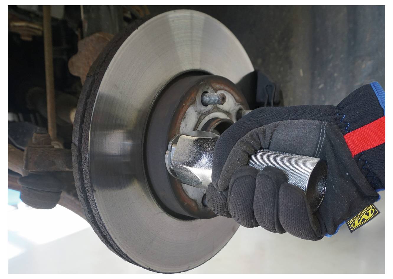 Ein Scheibenbremssystem eines Autos, das einen Bremsrotor und einen Bremssattel zeigt. Der Rotor ist leicht verschlissen, und der Bremssattel hält Bremsbeläge zur Anwendung.