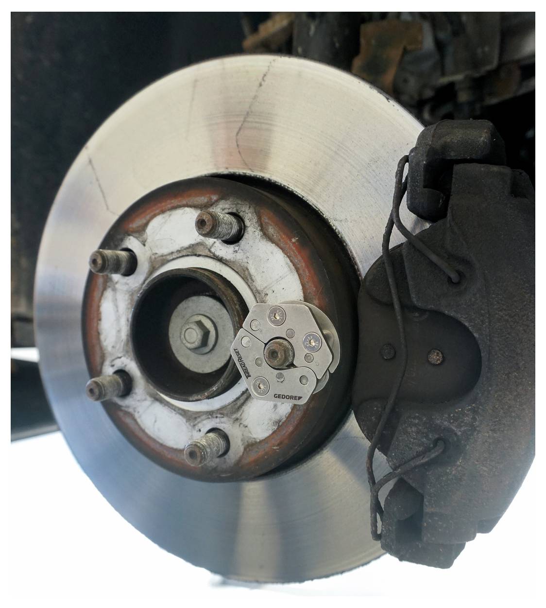 Scheibenbremse eines Autos mit sichtbarem Rotor und Bremssattel. Der Rotor ist silberfarben mit sichtbaren Nuten, und der Bremssattel befindet sich auf der rechten Seite.