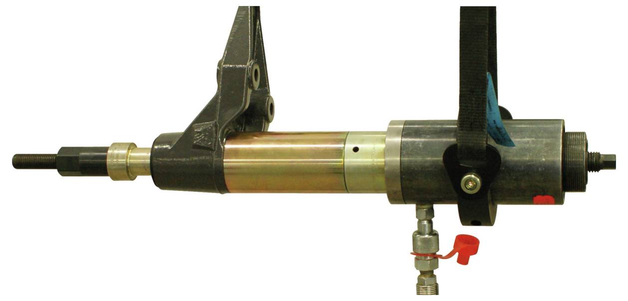 Eine Nahaufnahme einer mechanischen Werkzeugkomponente, die eine zylindrische Metallstruktur mit einem angebrachten Arm und einer Düse mit einem roten Ventil zeigt.