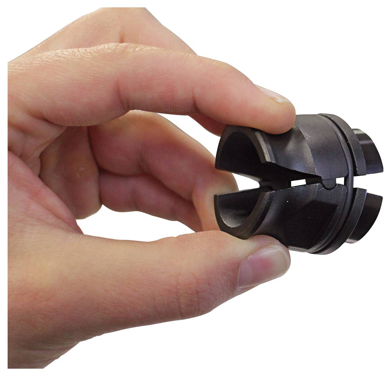 Eine Hand, die einen kleinen, schwarzen, zylindrischen Gegenstand mit zwei durchgeschnittenen Schlitzen hält, möglicherweise ein mechanisches Teil oder eine Werkzeugkomponente.