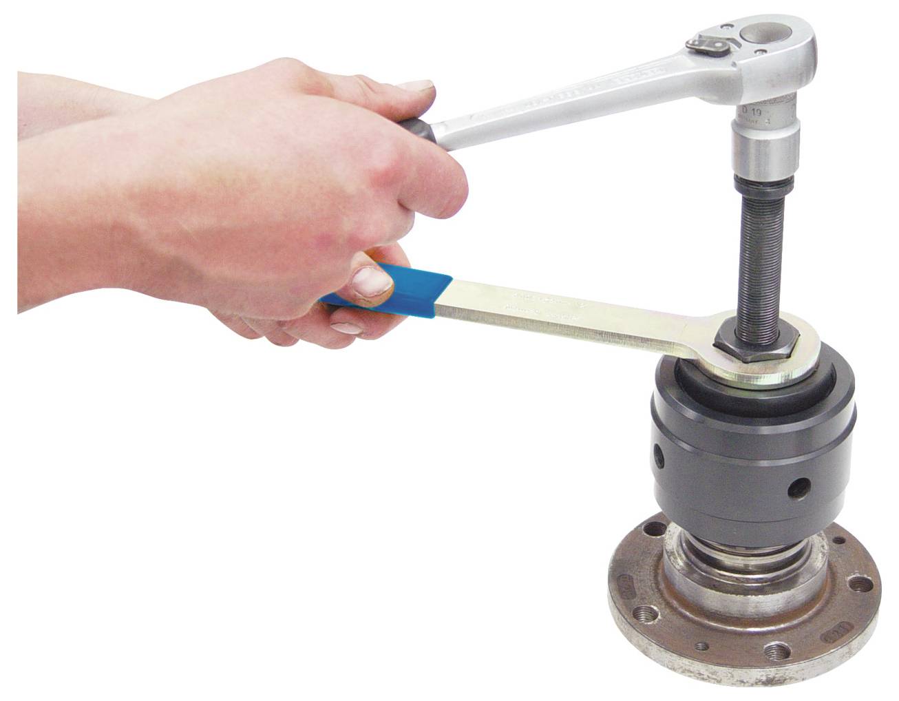 Eine Person verwendet einen Schraubenschlüssel und einen Ratschenschlüssel, um eine Schraube an einem mechanischen Bauteil oder Maschinenteil anzuziehen oder zu lockern.