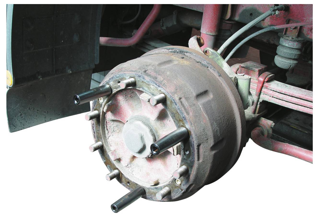 Eine Bremsrommelbaugruppe eines Fahrzeugs mit vorstehenden Achsenbolzen und einer verrosteten, zylindrischen Bremstrommel, die für die Funktion des Bremsmechanismus integral ist.