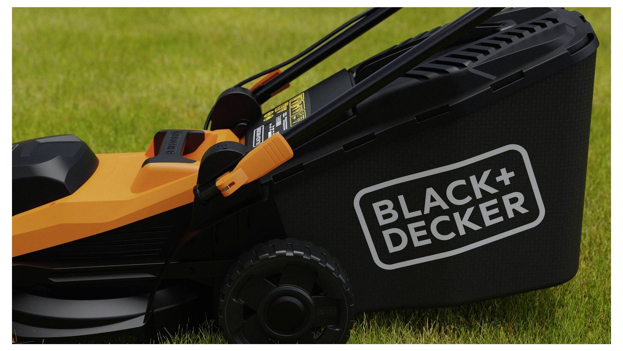 Eine Nahaufnahme eines Black+Decker-Rasenmähers auf einem grünen Rasen, die die Seite des Mähers mit seinem Markennamen auf dem Grassammelrucksack zeigt.
