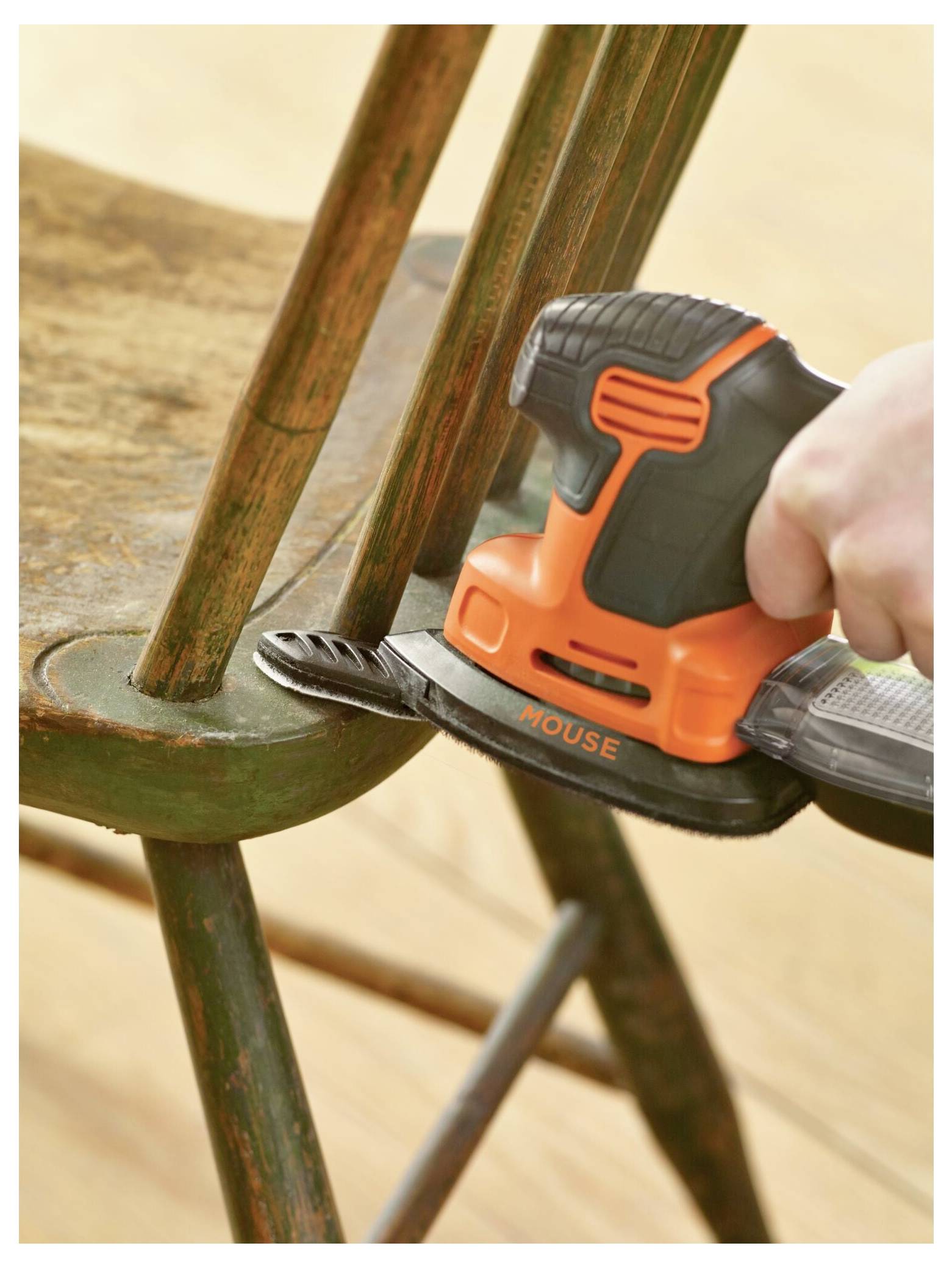 Die Hand einer Person, die einen Elektroschleiffer benutzt, um die Oberfläche eines Holzstuhls zu glätten.