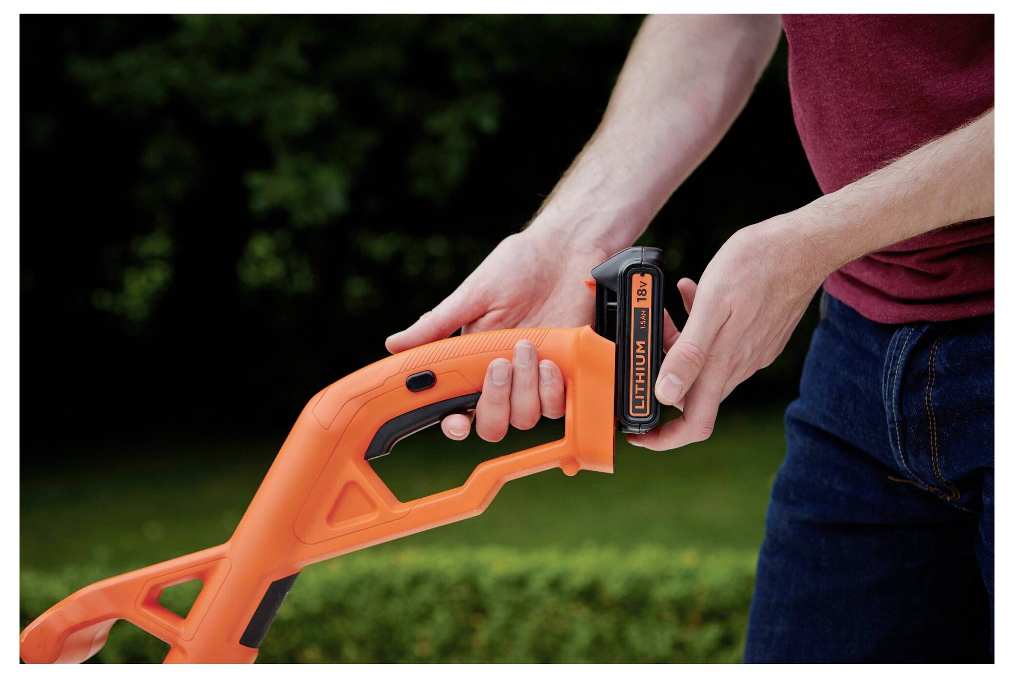 Ein Trimmer schneidet durch hohes grünes Unkraut, mit dem sichtbaren Markennamen „Black & Decker