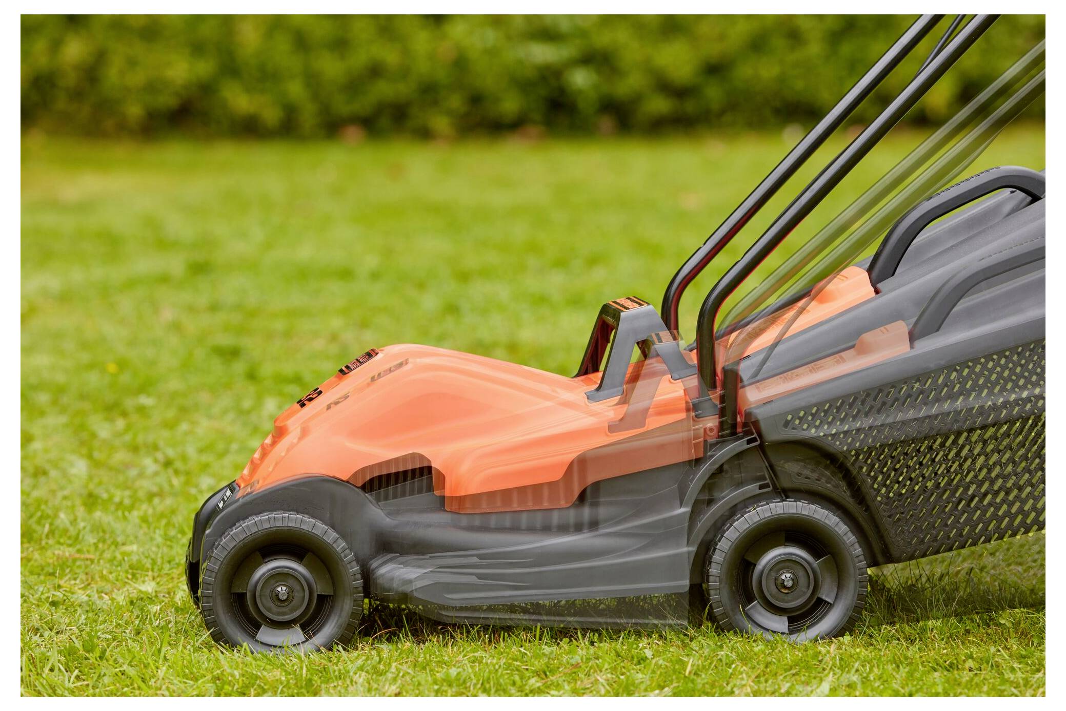 Ein unscharfes Bild eines orangefarbenen Rasenmähers in Bewegung auf einem Grasnarbenhof, das eine Bewegung über die linke Seite zeigt.