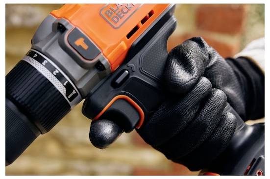 Eine behandschuhte Hand hält eine orange-schwarze Elektrobohrmaschine mit sichtbar eingestelltem Drehzahlregler auf Position 1. Der Fokus liegt auf dem Werkzeug und der Hand.