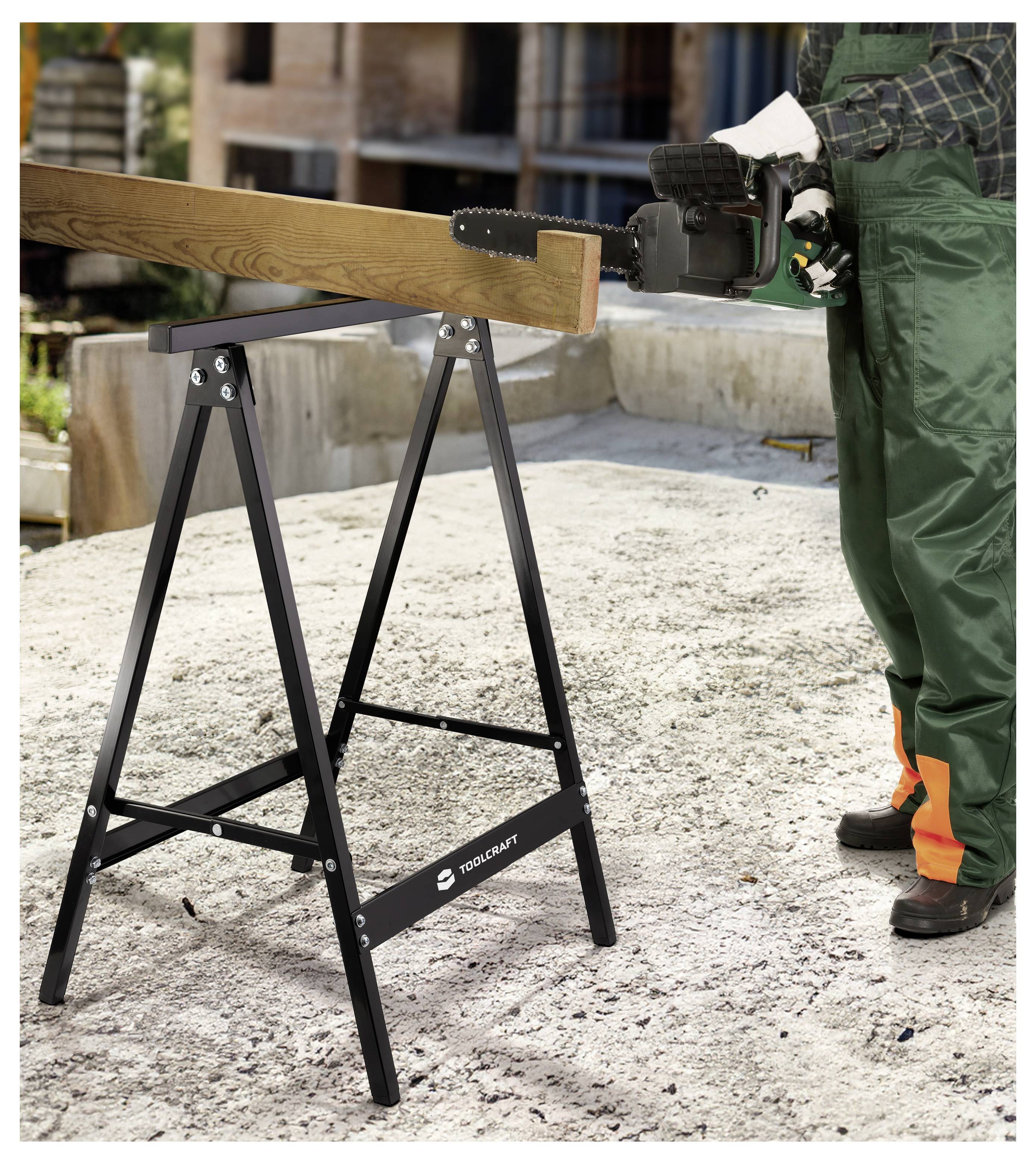 Arbeiter in Schutzausrüstung bedient eine Kettensäge zum Zuschneiden eines Holzbalkens, der auf einem Sägebock an einer Baustelle gestützt ist.