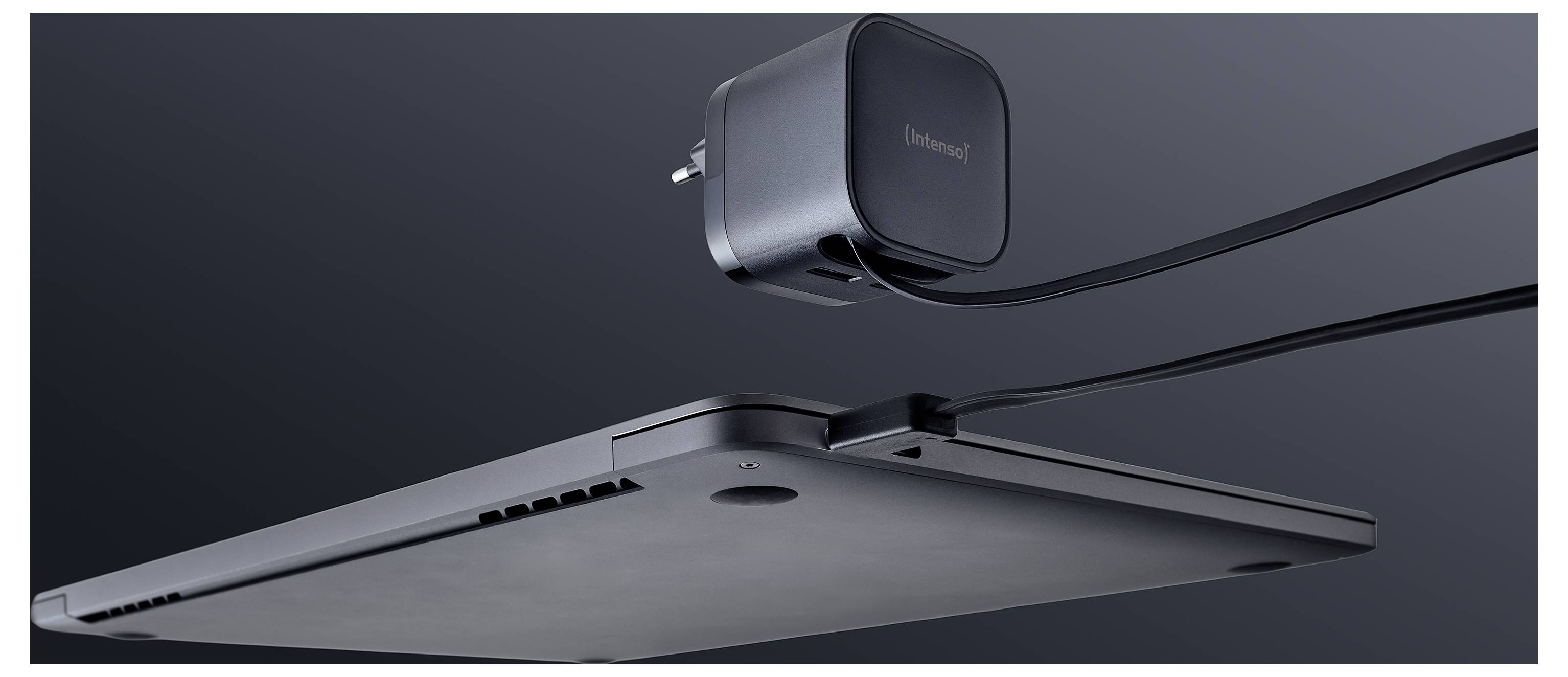 Ein dünner Laptop von der Seite betrachtet, der ein schlankes Profil zeigt, verbunden mit einem Netzteil durch ein Kabel, vor einem dunklen Hintergrund.