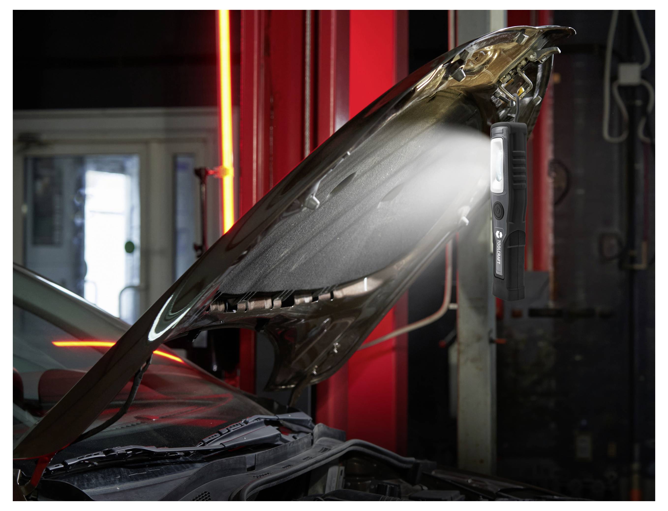 Motorhaube angehoben in einer Autowerkstatt, wobei der Motorraum unter hellen Inspektionsleuchten freigelegt ist.