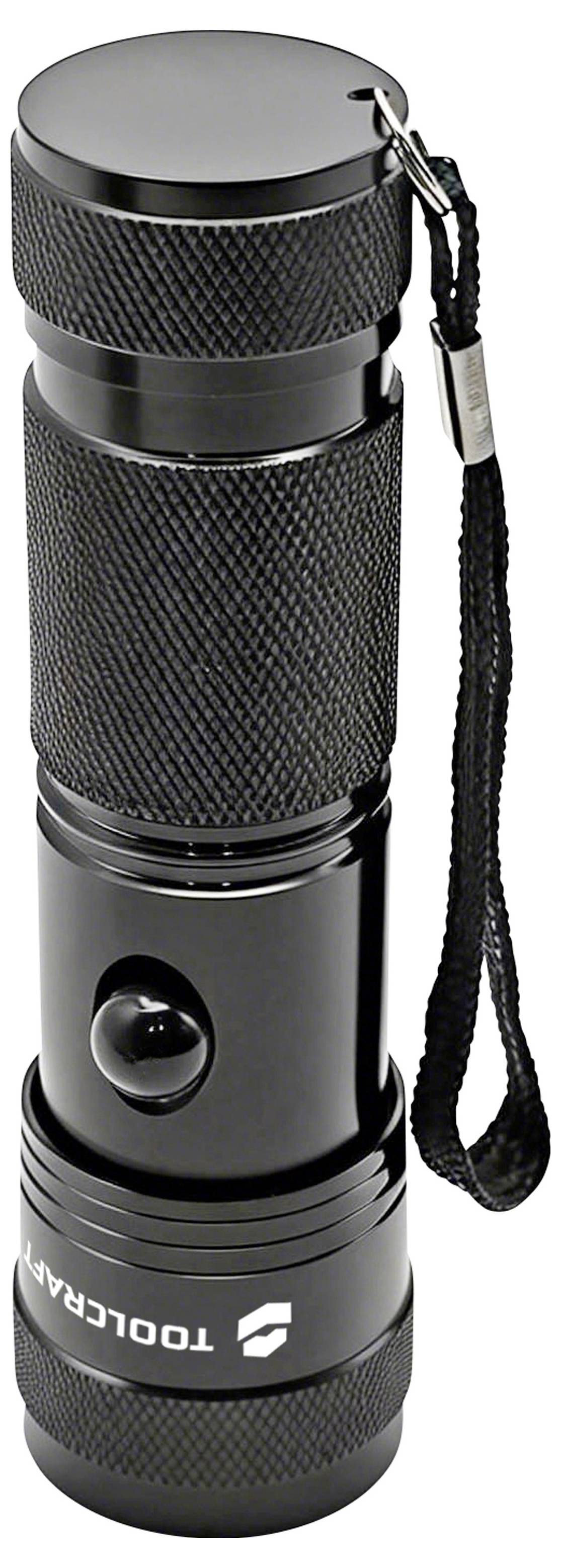 Schwarze zylindrische Metall-Taschenlampe mit strukturiertem Griff und Handgelenkschlaufe, aufrecht auf weißem Hintergrund dargestellt.