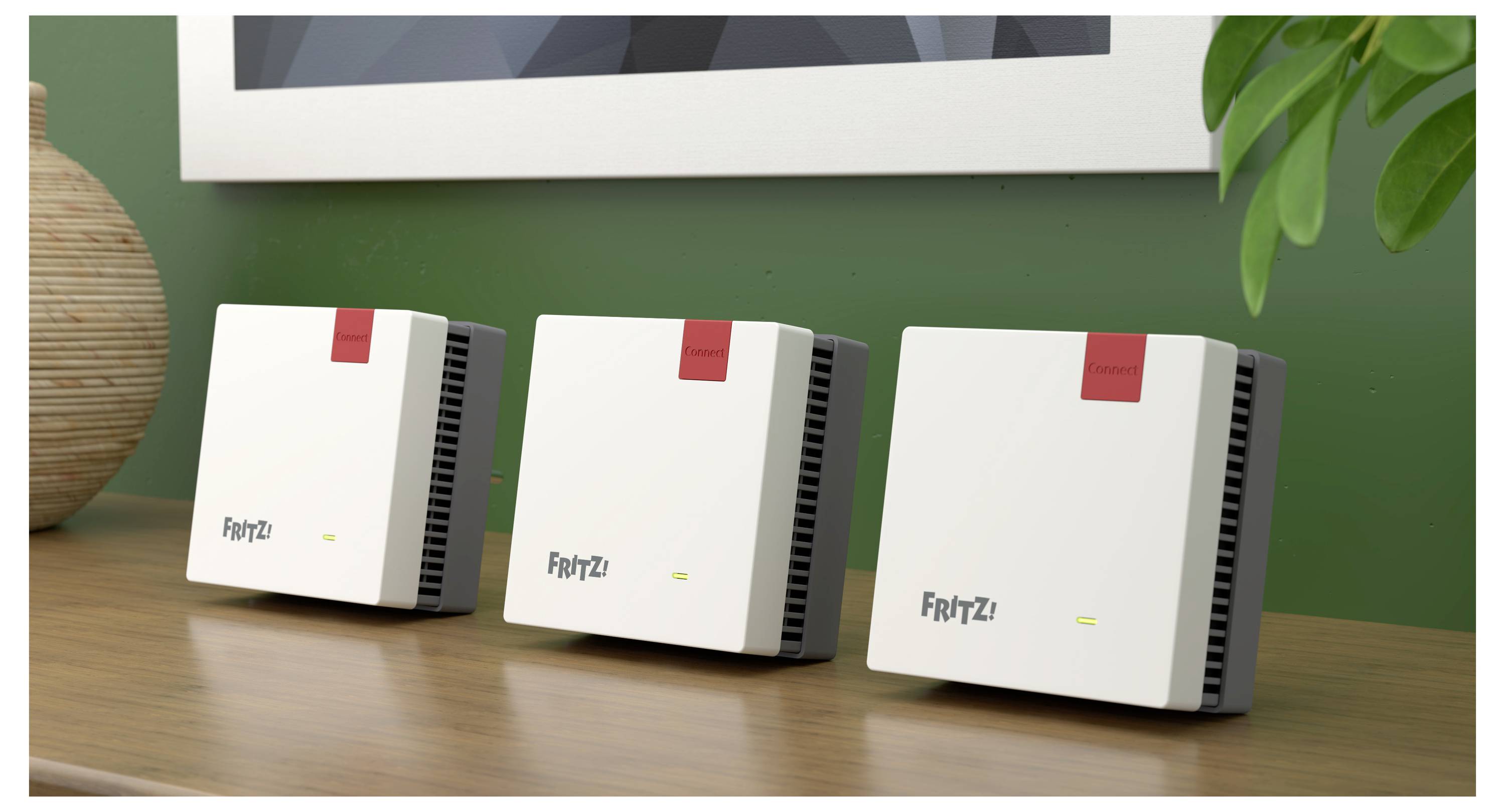Drei identische weiße Wi-Fi-Router mit roten Etiketten auf einem Holzregal, vor einer grünen Wand mit einer teilweise sichtbaren Pflanze.