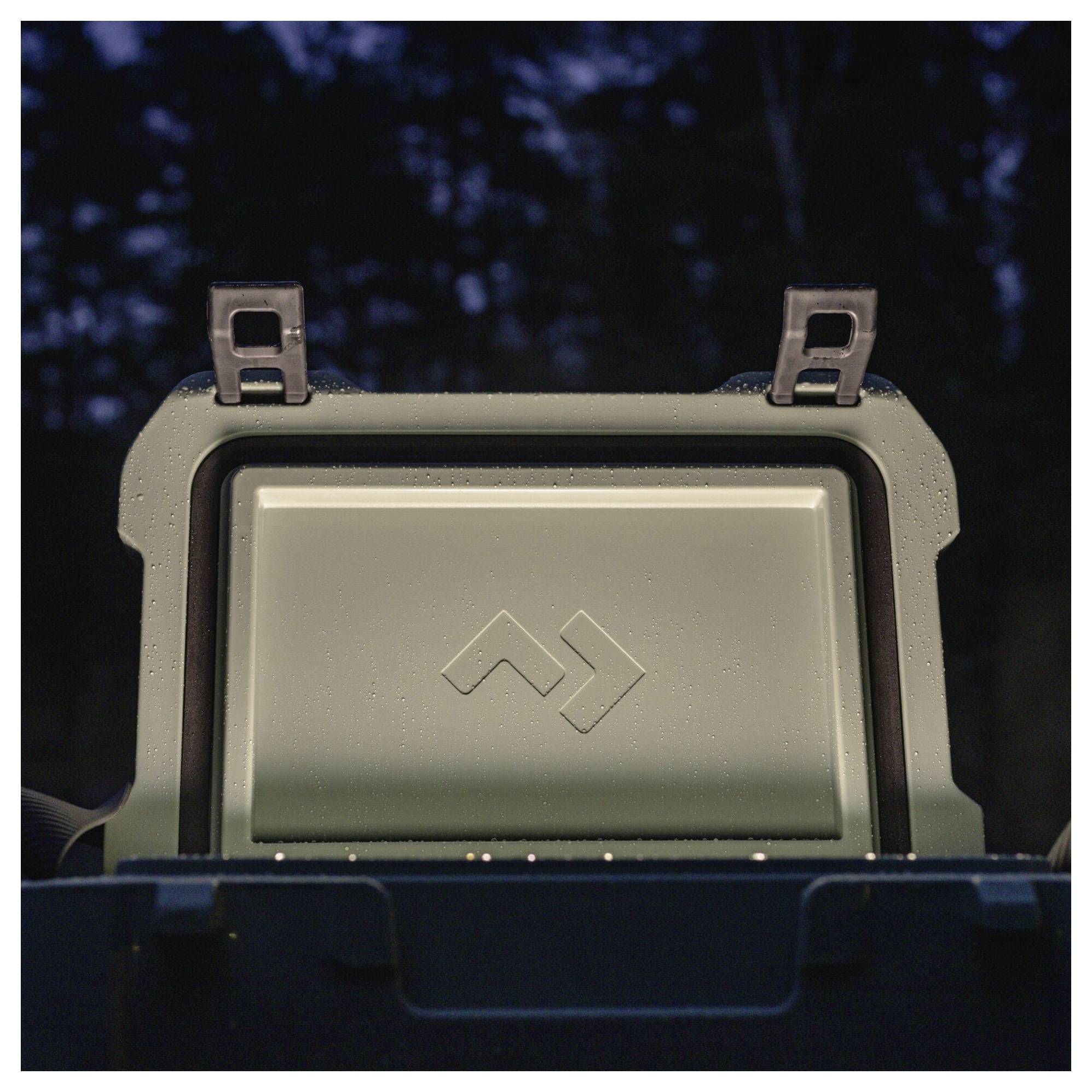 Nahaufnahme eines robusten grauen Geräts oder Gehäuses mit einem leeren Frontpanel und kleinem Logo, montiert vor einem dunkel unscharfen Hintergrund.