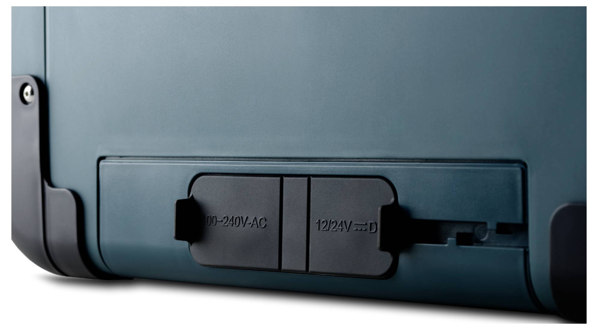 Nahaufnahme einer Seitenblende eines Geräts mit abgedeckten Anschlüssen mit den Beschriftungen „100–240V AC