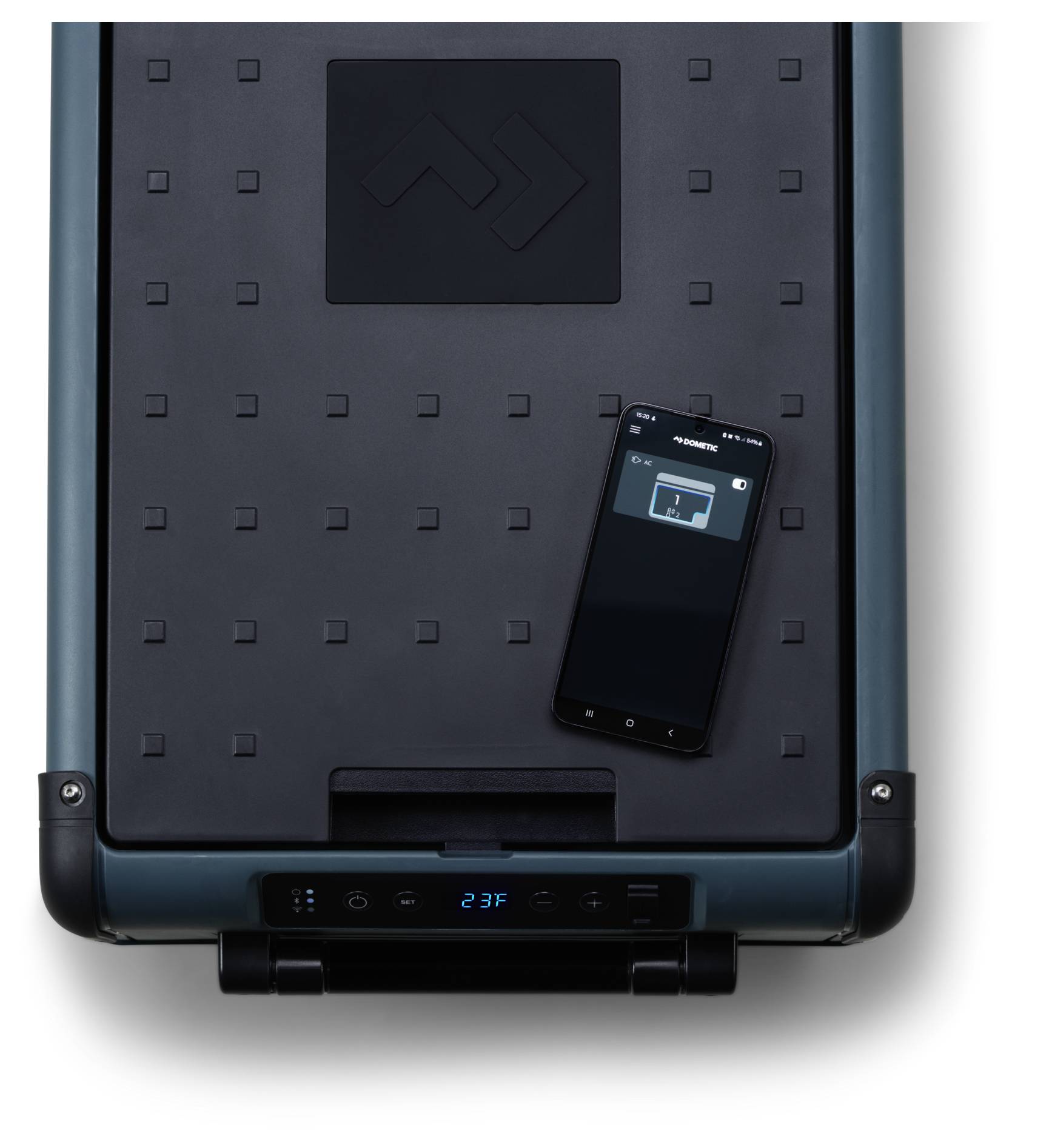 Ein Smartphone ruht auf einem großen dunklen rechteckigen Gerät mit digitaler Anzeige, was auf ein intelligentes Haushaltsgerät oder Trägergerät hindeutet.