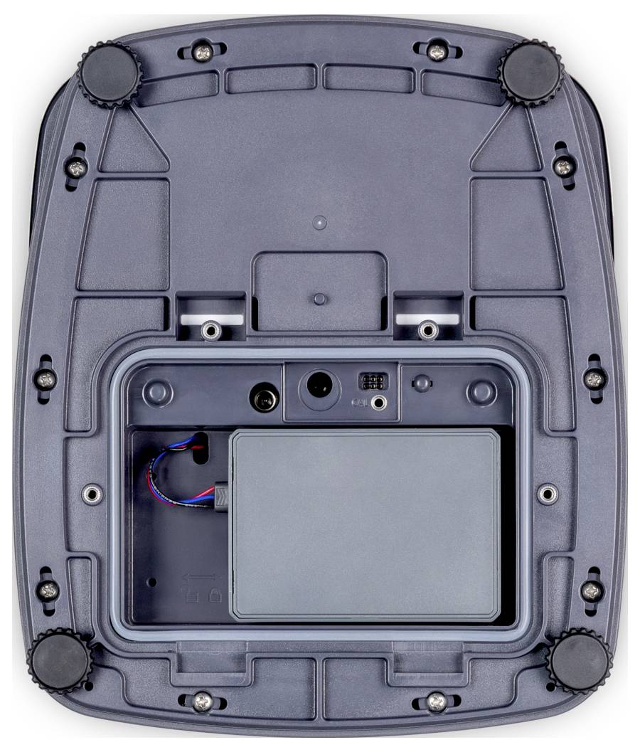 Das Bild zeigt die Unterseite eines Geräts mit sechs Füßen zur Stabilisierung und einem offenen Fach, in dem elektronische Komponenten untergebracht sind.