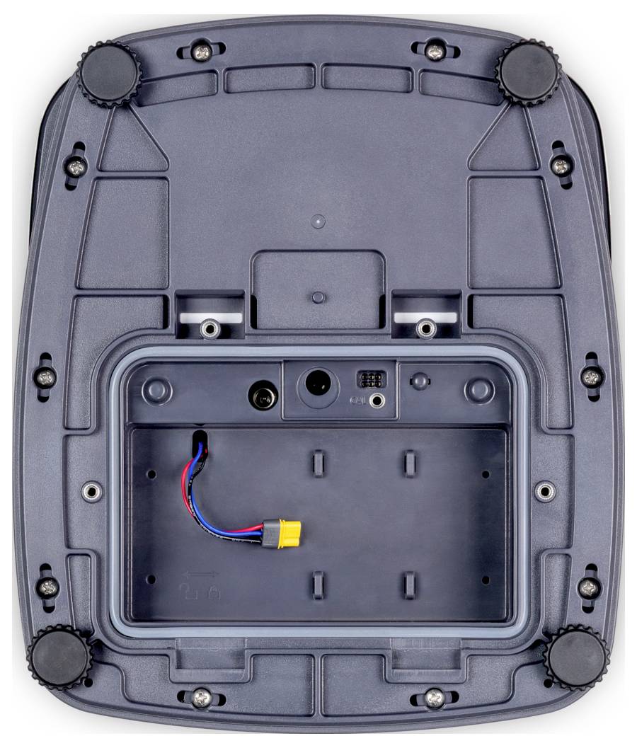 Das Bild zeigt die Unterseite eines elektronischen Geräts mit einem Fach für eine Batterie, mehreren Schrauben und Gumminoppen zur Stabilisierung.