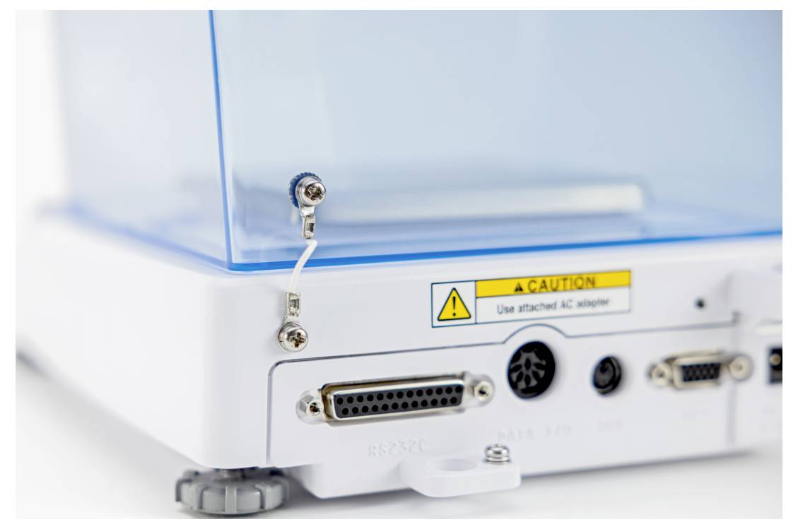 Nahaufnahme eines weißen elektronischen Geräts mit transparentem blauem Deckel. Es verfügt über verschiedene Anschlüsse, ein Warnschild und ein Vorsichtszeichen zur Verwendung des richtigen AC-Adapters.