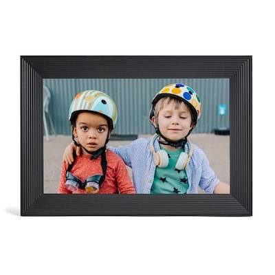 Zwei Kinder mit bunten Helmen stehen zusammen, eines mit dem Arm um das andere gelegt. Sie wirken beide entspannt und glücklich im Freien.