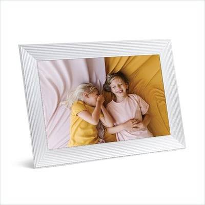 Ein gerahmtes Foto von zwei kleinen Kindern, die auf einem Bett liegen, lächeln und glücklich aussehen, wobei ein Kind ein gelbes Hemd und das andere ein rosa Kleidungsstück trägt.