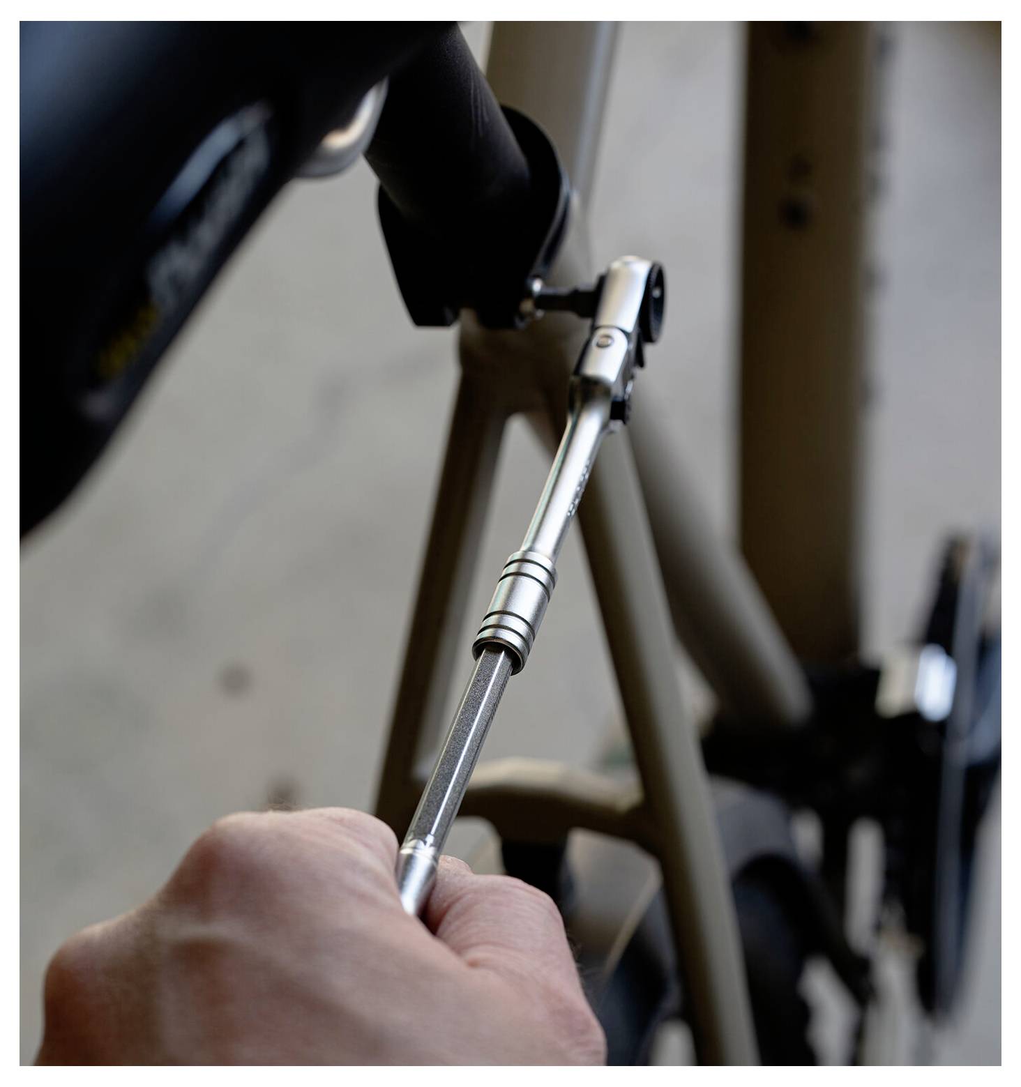 Nahaufnahme einer Person, die eine Fahrradschraube mit einem Schraubenschlüssel am Fahrradrahmen anzieht.