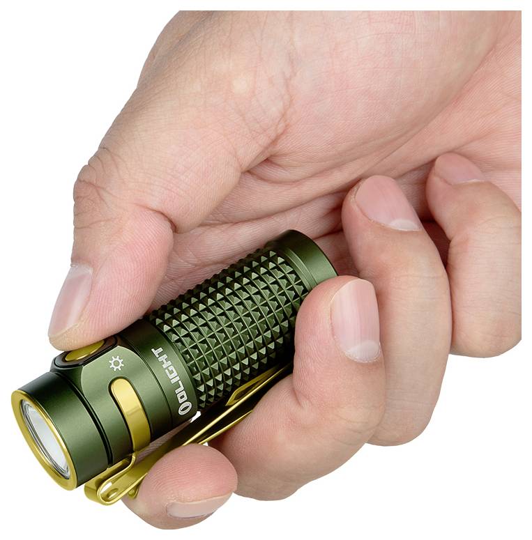 Eine Hand, die eine kleine, grüne strukturierte Taschenlampe mit einer goldfarbenen Klammer und einem Knopf hält, was die kompakte Größe und den einfachen Griff anzeigt.