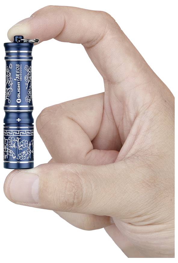 Eine Hand, die eine kleine, blaue Taschenlampe mit Blumenmuster hält; „Olight I3E EOS