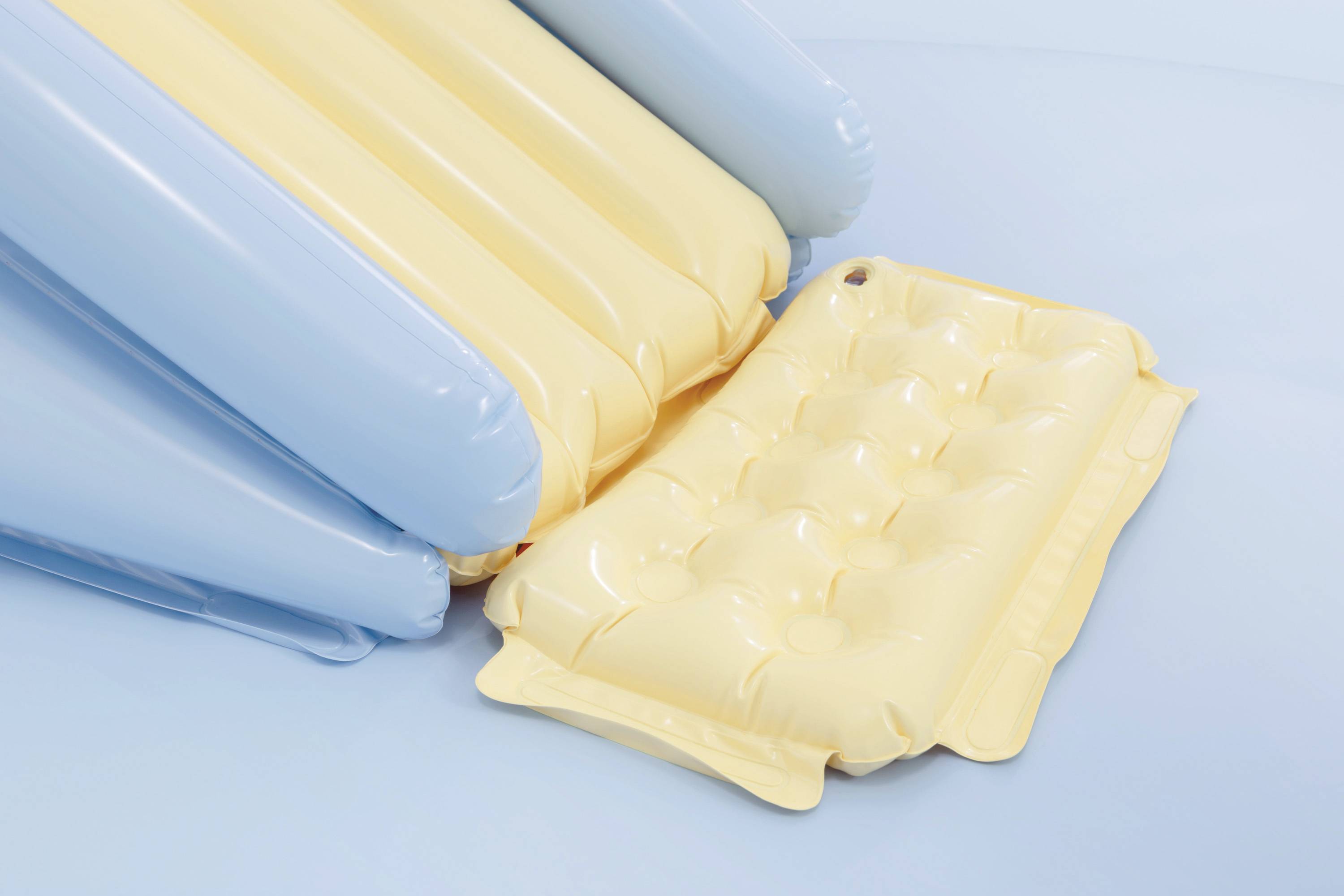 Gelbe und blaue aufblasbare Poolflöße auf einer hellblauen Oberfläche.