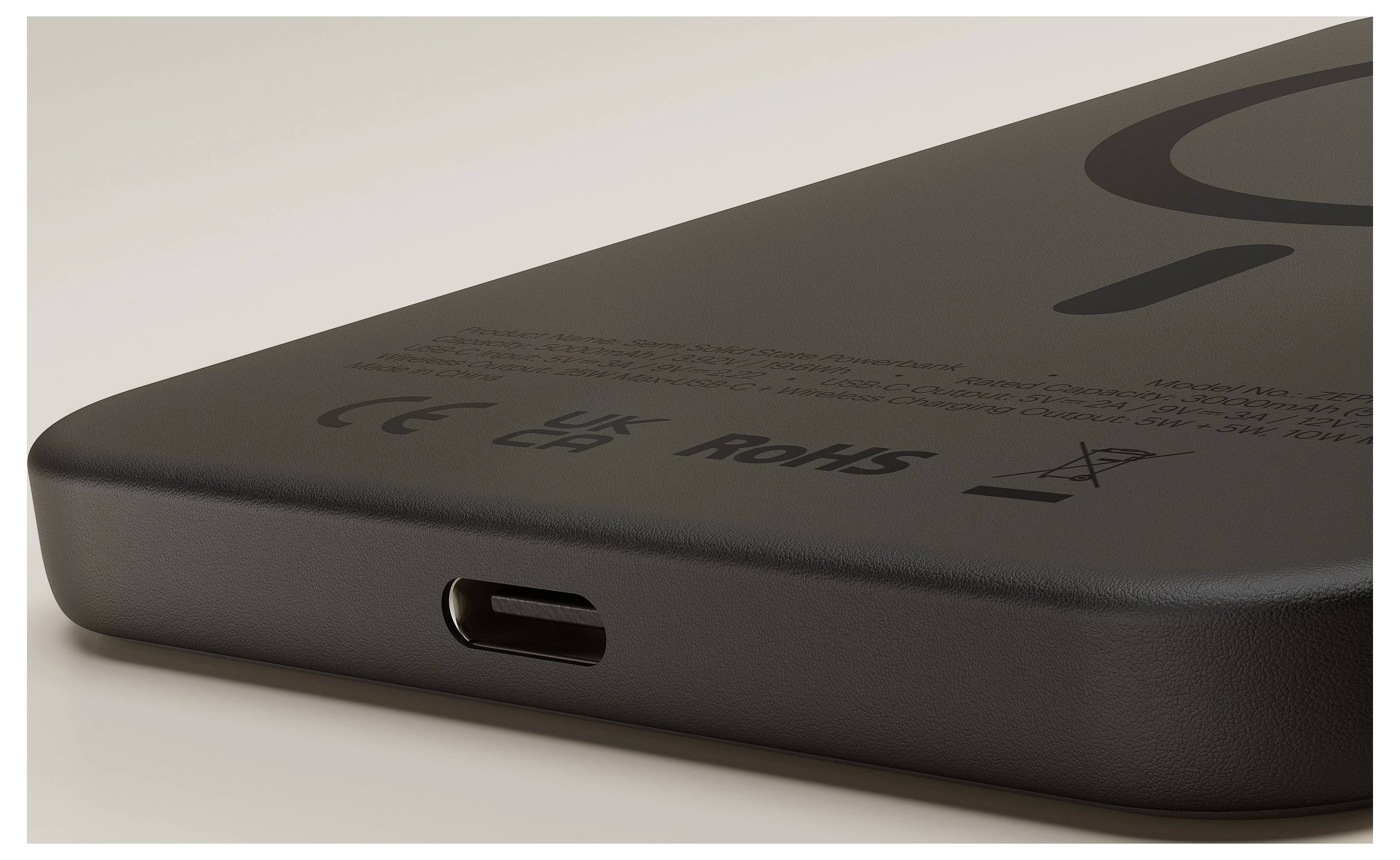 Nahaufnahme einer Ecke eines schwarzen Geräts oder einer Powerbank mit einem USB-C-Ladeanschluss und Konformitätskennzeichnungen auf der Rückseite.