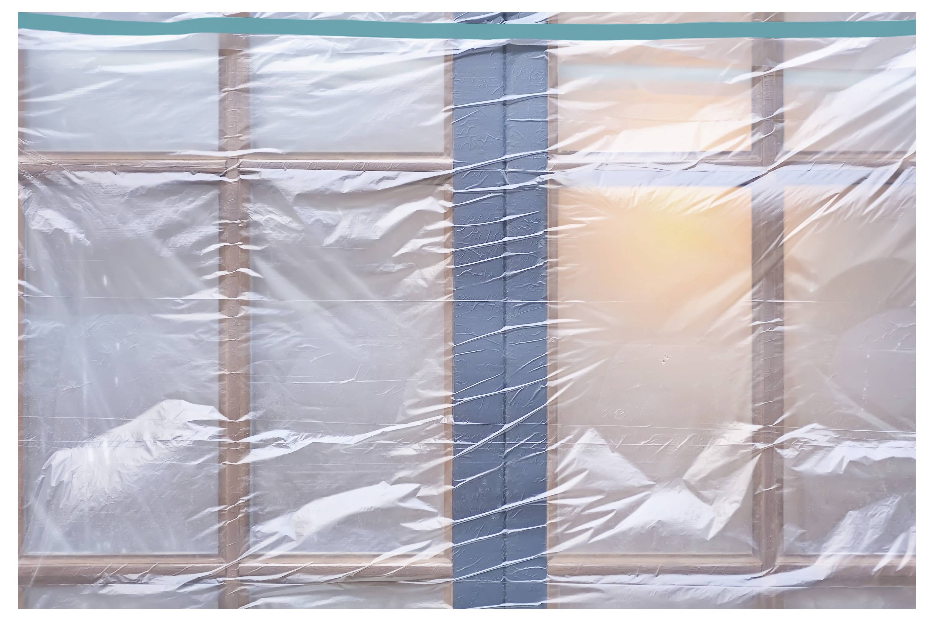 Fenster mit durchscheinender Schutzfolie bedeckt, mit Sonnenlicht, das durch das rechte Fenster scheint.