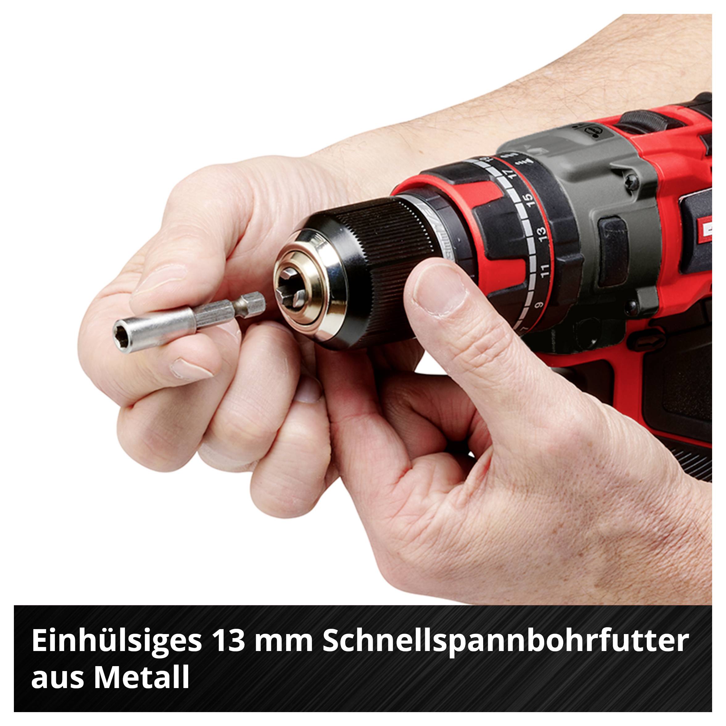 Ein Mann, der eine Schutzbrille und Handschuhe trägt, verwendet einen rot-schwarzen kabellosen Bohrer, um ein Loch in eine Betonwand zu bohren und erzeugt dabei Staub.