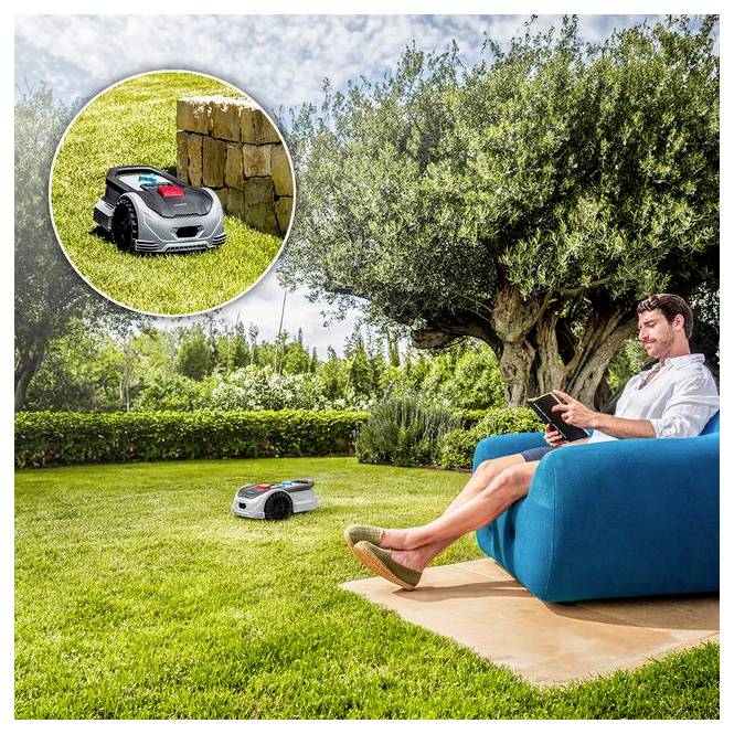 Eine Person entspannt sich auf einem blauen Außensofa, nutzt ein Tablet, während ein Roboter-Rasenmäher das Gras in einem sonnigen Garten autonom trimmt.