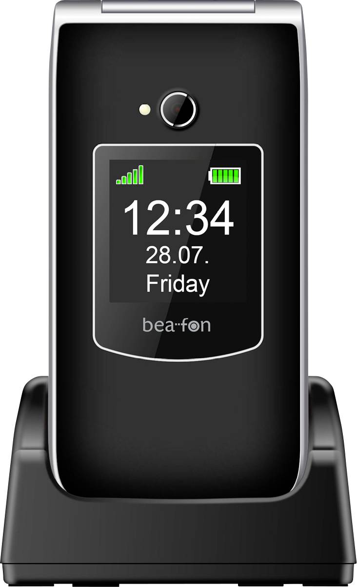 Ein schwarzes Klapphandy auf einer Ladestation zeigt die Uhrzeit '12:34' und das Datum '28.07. Freitag' an, mit Signal- und Batterieanzeigen.