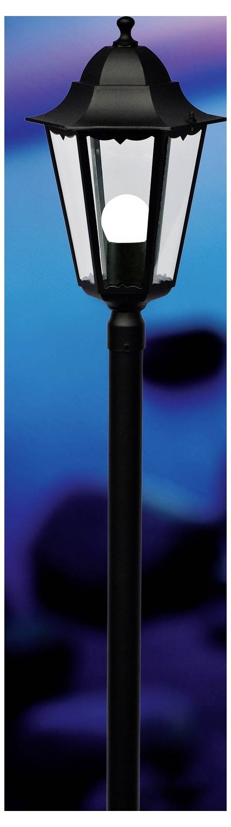 Eine schwarze Straßenlaterne mit einer leuchtenden weißen Glühbirne steht vor einem verschwommenen blau-violetten Hintergrund und erzeugt dadurch einen Kontrast.