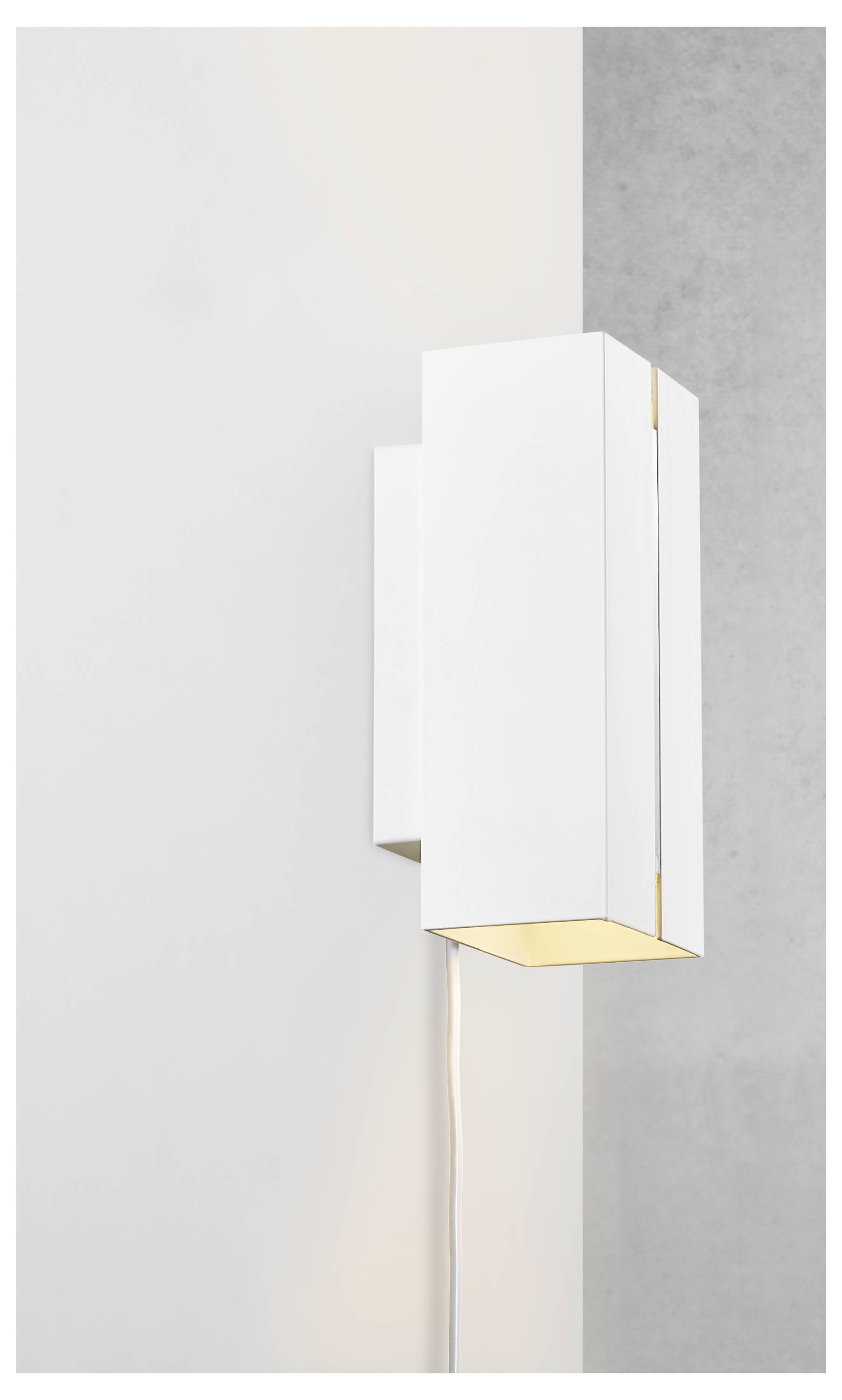 Eine moderne weiße Wandleuchte mit geometrischem Design ist an einer hellgrauen Wand montiert, wobei das Licht nach unten gerichtet ist.