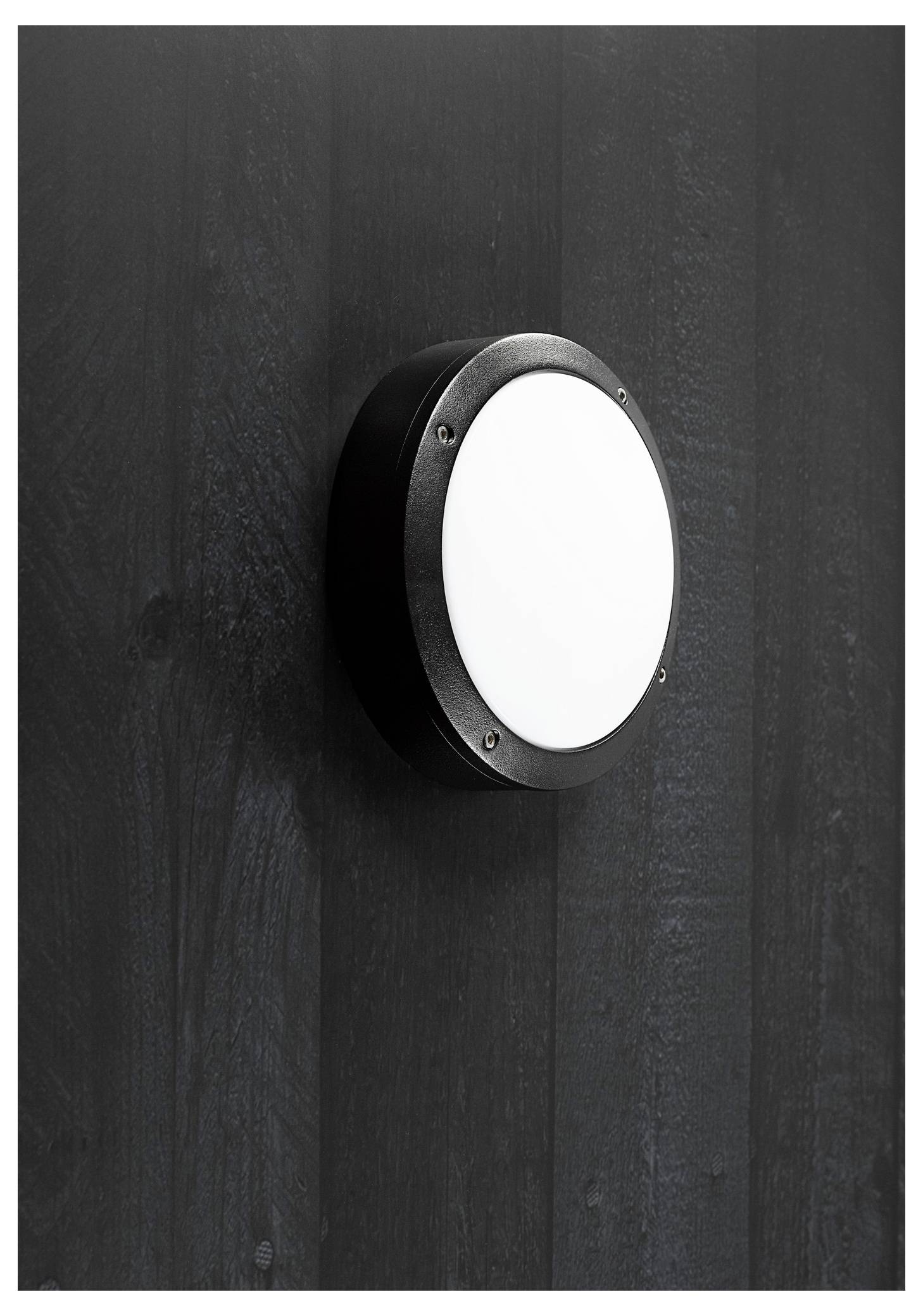 Eine runde, moderne schwarze Wandleuchte mit weißem Zentrum, montiert an einer strukturierten dunklen Wand. Das Design ist minimalistisch und elegant.